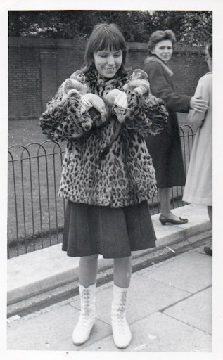 A girl in ice skates and a leopard-print coat holding two small monkeys