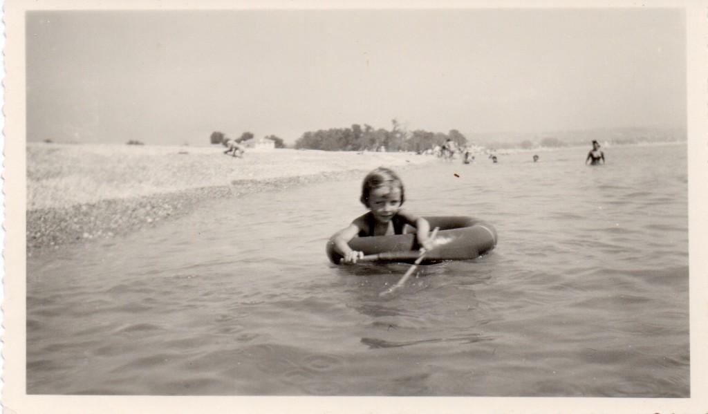 A girl floating in a rubber ring in the sea beside a pebble beach